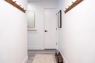 a hallway with white walls and a door and a rug at Escape to Revy - Beautifully Designed Condo in Revelstoke