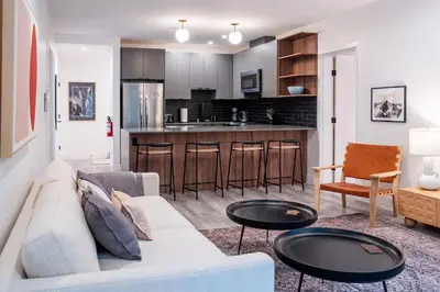 a living room and kitchen with a couch and tables at Snow & Swing Getaway - Three Bedrooms with Hot Tub (Stay Revy) in Revelstoke