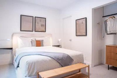 a white bedroom with a bed and a wooden bench at Snow & Swing Getaway - Three Bedrooms with Hot Tub (Stay Revy) in Revelstoke