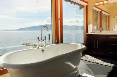 a bath tub in a bathroom with a large window at Exclusive Private Island - Pacific Ocean Paradise in Madeira Park