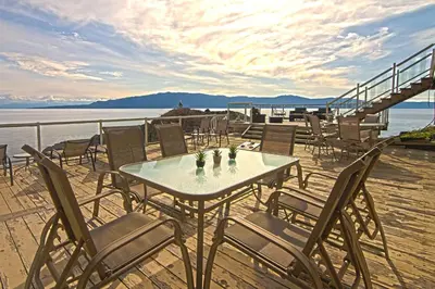 a table and chairs on a deck next to the water at Exclusive Private Island - Pacific Ocean Paradise in Madeira Park