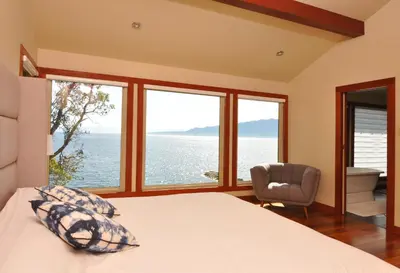 a bedroom with a bed and a view of the ocean at Exclusive Private Island - Pacific Ocean Paradise in Madeira Park