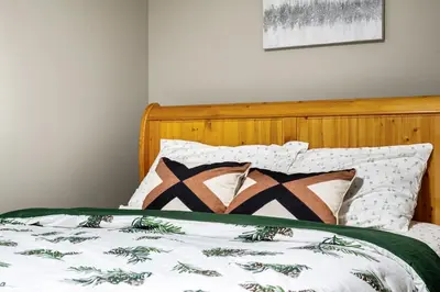 a bed with a wooden headboard and pillows on it at Newly renovated 2 bedroom basement suite in Calgary