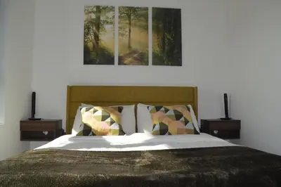 a bedroom with a bed with two nightstands and a painting at Stokeside Serenity in Revelstoke
