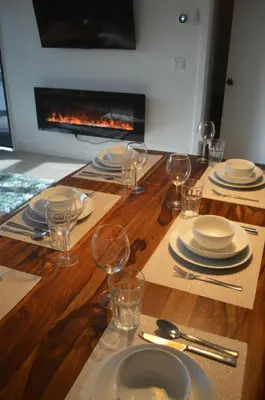 a wooden table with plates and glasses and a fireplace at Stokeside Serenity in Revelstoke