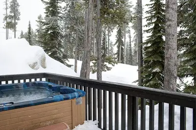 a hot tub on a deck in the snow at Alpine Timber Luxury Chalet w/Hot Tub in Big White