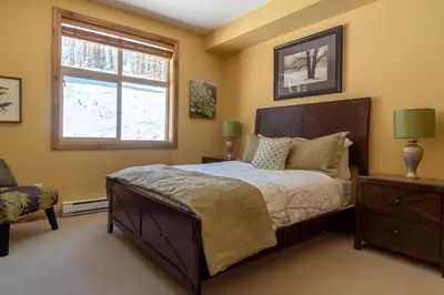 a bedroom with a large bed and a window at The Aspens 5 w/ Hot Tub in Big White