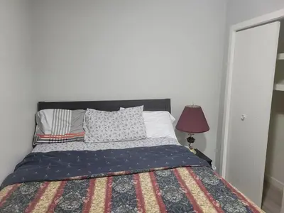 a bedroom with a bed with a quilt and a lamp at Brand New 2 Bedroom Basement Suite with Wifi in Edmonton