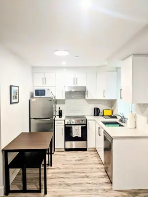 a kitchen with white cabinets and a wooden table at 2 Bed Apartment Free Parking Central Location in Vancouver