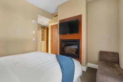 a bedroom with a bed and a fireplace with a tv at Adventurer's Escape~ Mountain Luxury Resort in Canmore
