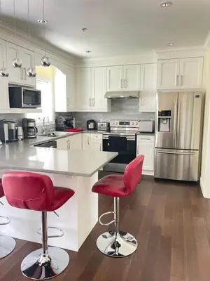 a kitchen with white cabinets and red bar stools at Arbutus summer house in Vancouver