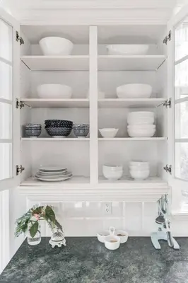 a white cabinet filled with plates and bowls at Emerald Bay Luxury Retreat with Hot Tub in Calgary