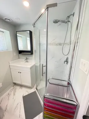 a bathroom with a shower with a bench and a sink at Arbutus violet room in Vancouver