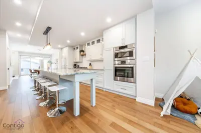 a kitchen with white cabinets and a large island with bar stools at The Azure, Near DT & University, TWO King Beds! in Edmonton