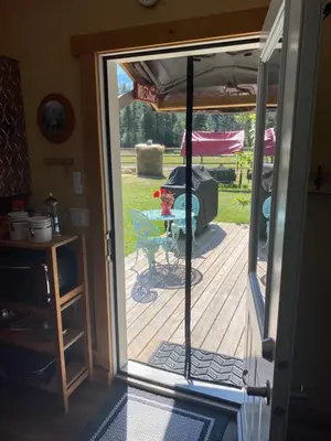an open door to a deck with a table and a grill at 1868 Noble Cottage in Clearwater