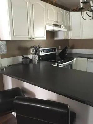 a kitchen with white cabinets and a black counter top at Whitehorse Wonder in Whitehorse