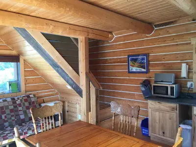 a dining room in a log cabin with a table and a microwave at Cabins Over Crag Lake in Carcross