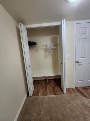 a room with a closet with a door and a rug at Basement Room in Calgary