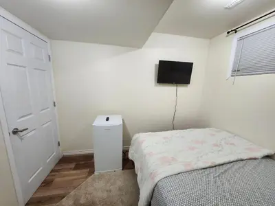 a bedroom with a bed and a tv on the wall at Basement Room in Calgary