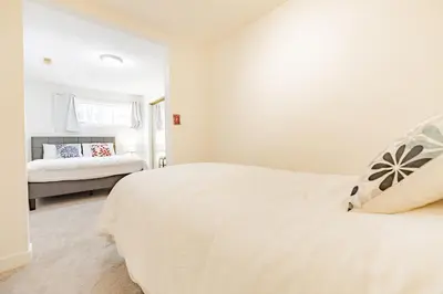 a white bedroom with a bed and a window at Walkout Basement Suite, 2 BDR 4BD, Bright and Spacious in Calgary