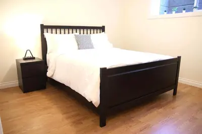 a bed with a black frame and a white comforter at A private suite in Port Moody in Port Moody