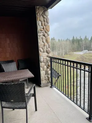 a porch with a table and chairs and a stone wall at Family friendly 2BR/2BA condo - Views & Location!! in Canmore