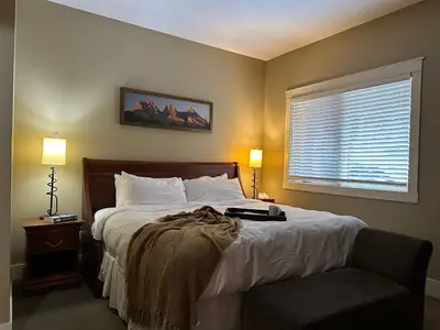 a bedroom with a bed and a window and a chair at Solara Escape - 2BR Retreat with Pool - Hot Tub - Gym - Spa in Canmore