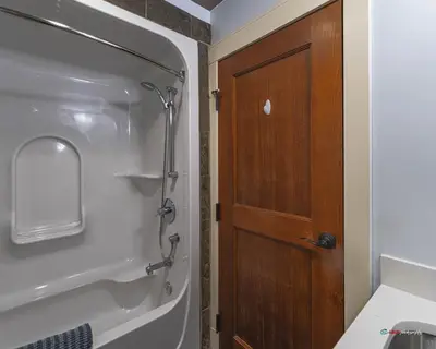 a bathroom with a shower and a wooden door at Solara Suite with Indoor Pool / Hot tub / Parking in Canmore