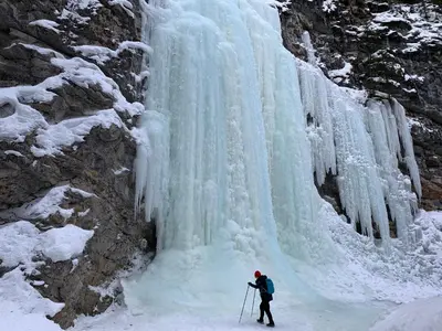 a person is standing in front of a frozen waterfall at Solara Suite with Indoor Pool / Hot tub / Parking in Canmore