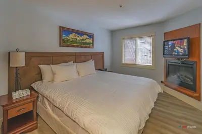 a bedroom with a large bed and a fireplace at Solara Studio with Pool/Hot tub/Parking/Gym in Canmore