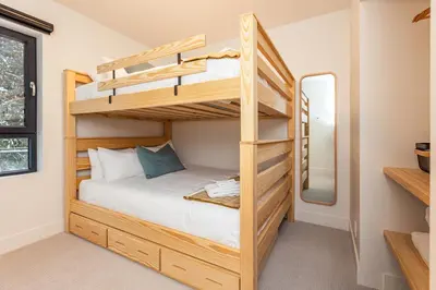 a bedroom with two bunk beds and a mirror at Tally Ho by Revelstoke Vacations in Revelstoke