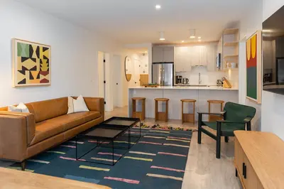 a living room with a couch and a table and a kitchen at Tally Ho by Revelstoke Vacations in Revelstoke
