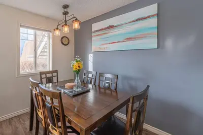 a dining room table with chairs and a vase of flowers at B211 MTN View ground floor town house- 2BD, Sleeps 8, hot tub, free parking, close to Banff in Canmore