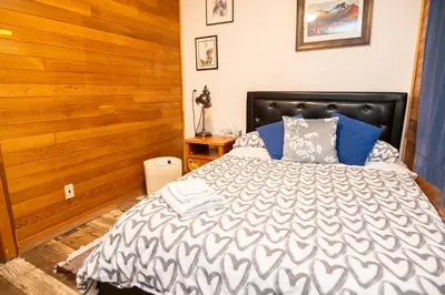 a bedroom with a bed with a wooden wall at 3 Bedroom Gardenside Downtown Home in Whitehorse