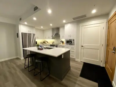 a kitchen with white cabinets and a kitchen island with bar stools at Luxury unit in the heart of Canmore in Canmore