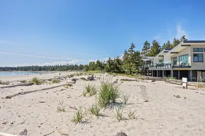 a beach in front of a house with a building at Ocean View Townhouse #26 at THE BEACH HOUSE in Campbell River