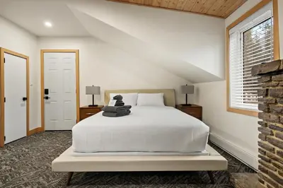 a bedroom with a white bed with a teddy bear on it at Elkhorn Lodge Vacation Rentals in Banff
