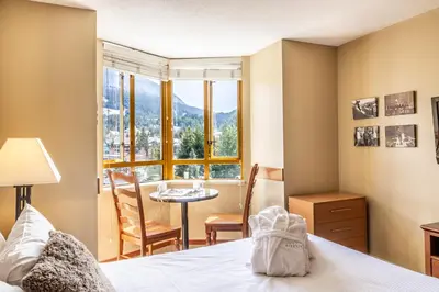 a bedroom with a bed and a table and a window at Cascade by Elevate Vacations in Whistler