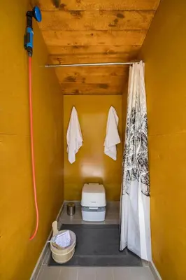 a small bathroom with a toilet in a yellow wall at Stay Wilder Sunshine Coast in Sechelt