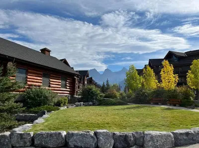 a yard with a stone retaining wall in front of a house at Mountain Escape sleeps 10 Guests in this 3BD 2BT Top Floor Condo with Mountain View in Canmore