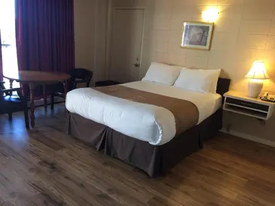 a hotel room with a large bed and a table at Siesta Motel in Olds