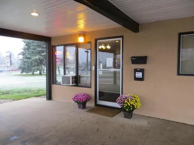 a front door of a store with two potted flowers at Siesta Motel in Olds