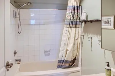 a bathroom with a tub and a shower curtain at Ponderosa Inn by Okanagan Premier in Big White