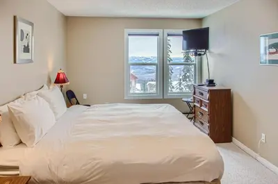 a bedroom with a large white bed and a window at Ponderosa Inn by Okanagan Premier in Big White