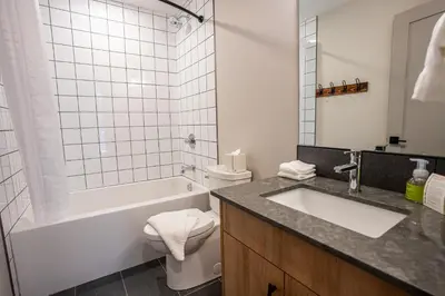 a bathroom with a sink and a tub and a toilet at Basecamp Suites Revelstoke in Revelstoke