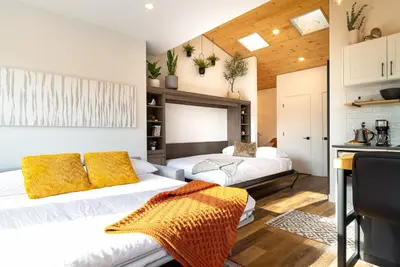 a living room with two beds and a kitchen at Coastal Creative Garden Studio in Colwood