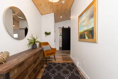 a hallway with a mirror and a chair at Coastal Creative Garden Studio in Colwood