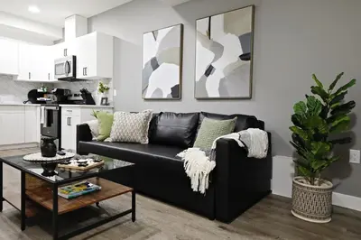 a living room with a black couch and a table at Queen Suite 20 Min from YEG Airport with Disney in Edmonton