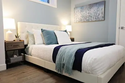 a bedroom with a white bed with blue and white pillows at Queen Suite 20 Min from YEG Airport with Disney in Edmonton