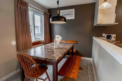a kitchen with a table with chairs and a counter at Mountain View 3br Loft Walk To Dt king fireplace in Canmore